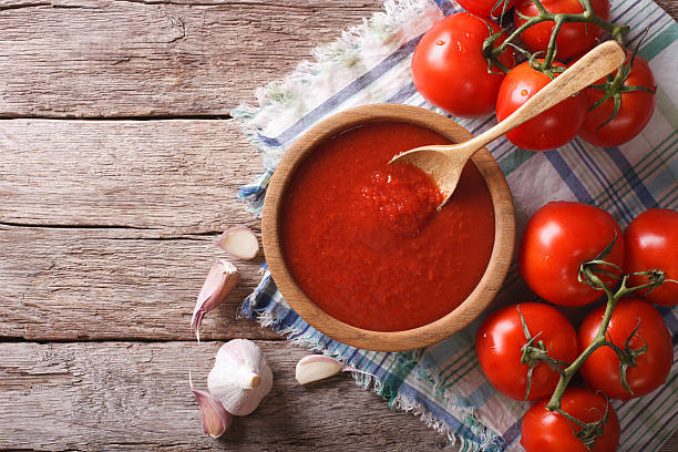 tomato sauce with garlic and basil in wooden bowl. horizontal tomato sauce with garlic and basil in a wooden bowl. horizontal view from above cooking with garlic stock pictures, royalty-free photos & images