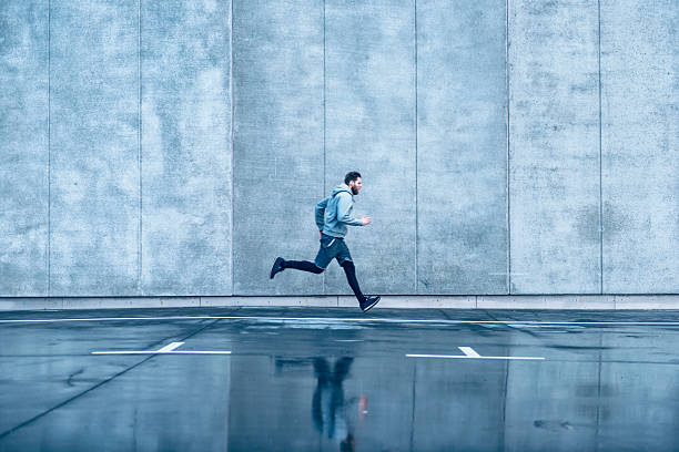 istock Male runner runs fast in front of concrete building 513751364