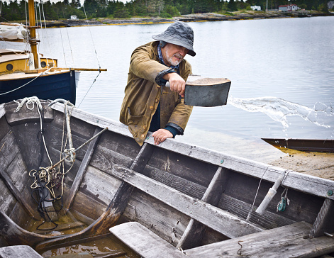 Fisherman Bailing a Dory, Mahone Bay, Nova Scotia.  All gear and clothing is authentic to the era.