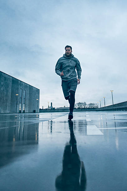 hombre de corredor un una rápida ejecución en la lluvia - running jogging urban scene city life fotografías e imágenes de stock
