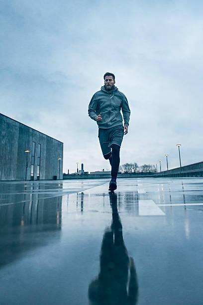 masculino atleta fora de uma rápida execução da chuva - running jogging urban scene city life imagens e fotografias de stock