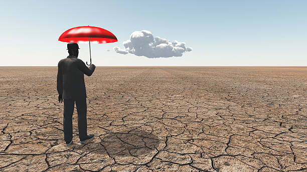 istock Man in desert with umbrella and single cloud 513752319