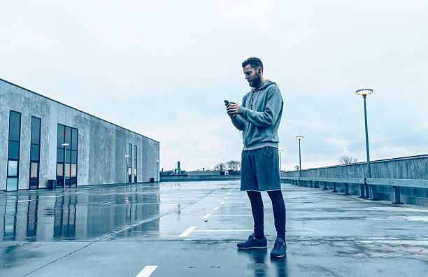 Male runner plays with smart phone before run