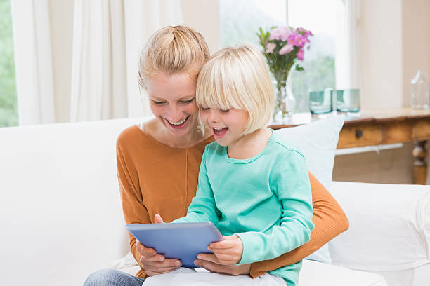 istock Happy mother and daughter on the couch using tablet 513753817