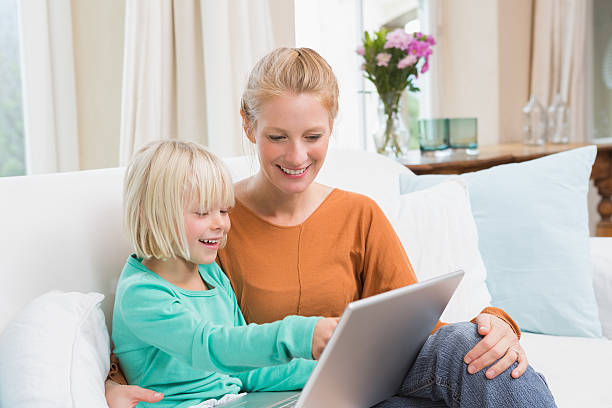 istock Happy mother and daughter on the couch using laptop 513753819