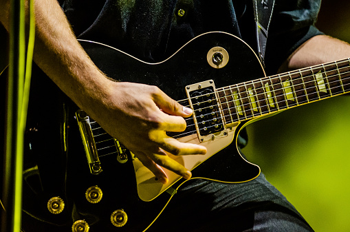 A close up on a musician's electric guitar while he his playing