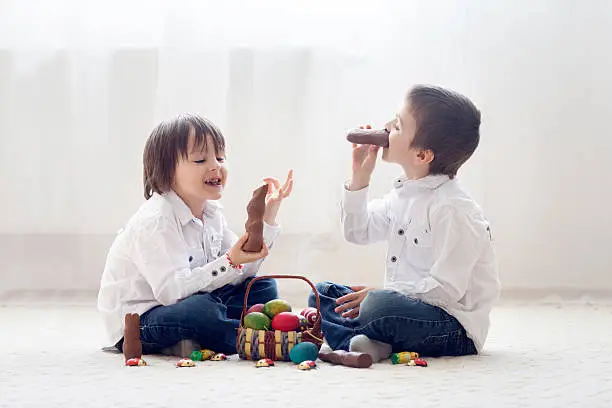 Photo of Two adorable little children, boy brothers, having fun eating ch