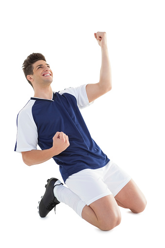 Athletic football player cheering over white background