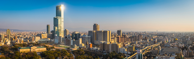 Warm sunset light illuminating the crowded cityscape of central Osaka, from the futuristic towers of Abeno Harukas, Japan's tallest skyscraper, across the leafy green oasis of Tennoji Park to the elevated highways and endless rooftops of Abeno-ku. ProPhoto RGB profile for maximum color fidelity and gamut.