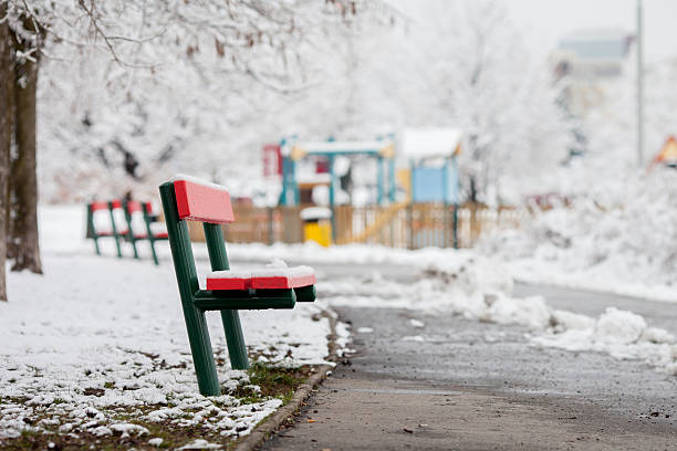 istock Red bench in a snowy park, children playground in background 513755568