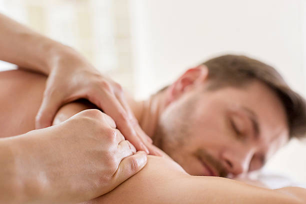 jovem está a gostar da massagem - massaging massage therapist rear view human hand imagens e fotografias de stock