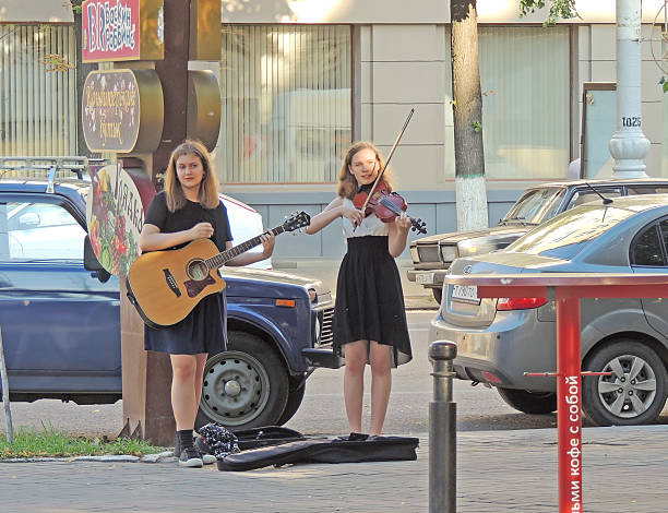 Voronezh, Russia - July 17, 2015: Two girls with a guitar and a violin playing on the sidewalk of the street