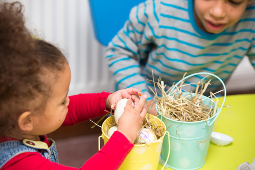 A close-up of a biracial little boy and girl doing craft at Easter.