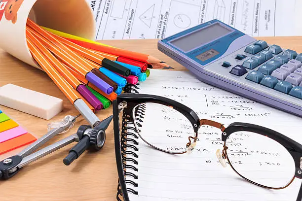 Photo of Glasses, Math Equation Notebooks and office Stationery on wood table.