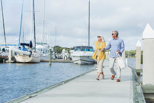 Happy senior couple walking along harbor holding hands