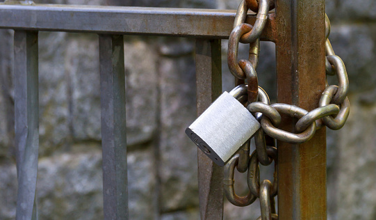 Metal padlock and chain on metal gate.