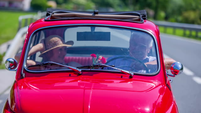 Senior couple enjoying the conversation in a red zastava car