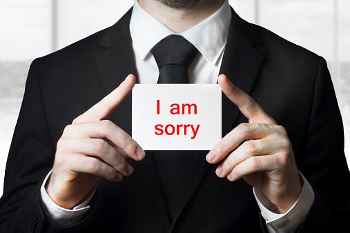 businessman in black suit holding sign i am sorry