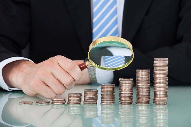 istock Businessman Examining Coins Stacked As Bar Graph 513788671