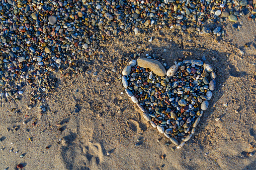 Heart of pebbles on the golden and soft sand on the beach