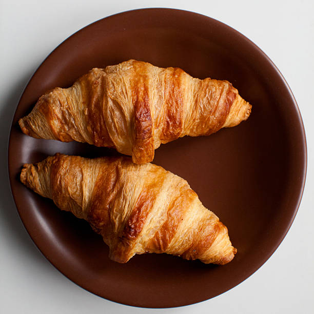 istock Two croissants on brown plate 513796304