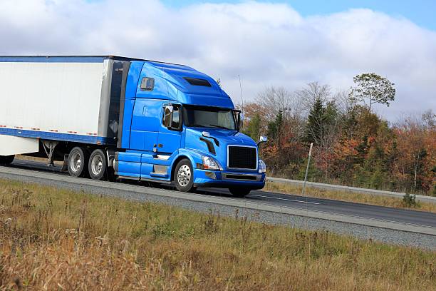istock Semi truck on a highway trees in background 513801160