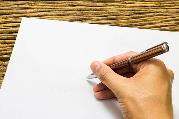 istock Hands with pen over paper on wooden background 513803330
