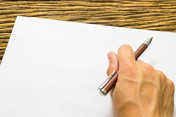 istock Hands with pen over paper on wooden background 513803500