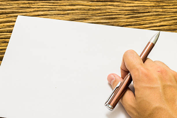 istock Hands with pen over paper on wooden background 513803510