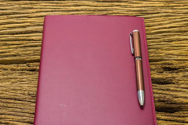 Photo of Pen on book on old wooden background