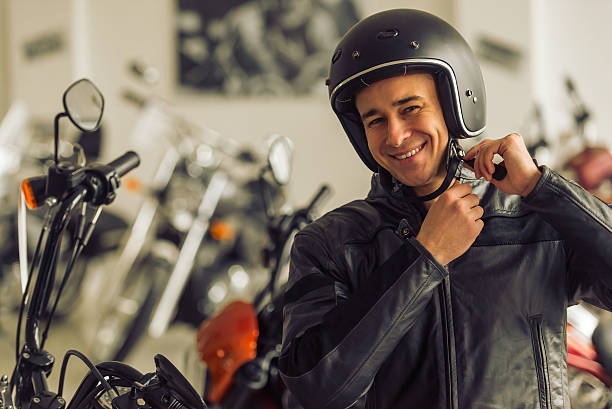 a man in a leather jacket and helmet is adjusting his helmet