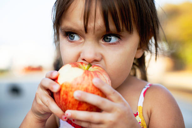 istock Little Girl is Biting a Red Apple 513805590