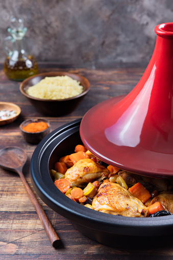 Tagine with cooked chicken and vegetables. Traditional moroccan cuisine. Wooden background Copy space