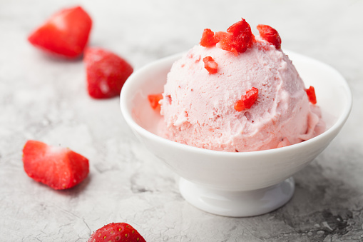 Strawberry sundae ice cream in bowl on white stone background Copy space