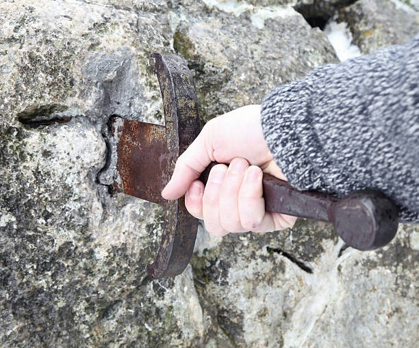 istock knight tries to remove Excalibur sword in the stone 513813160