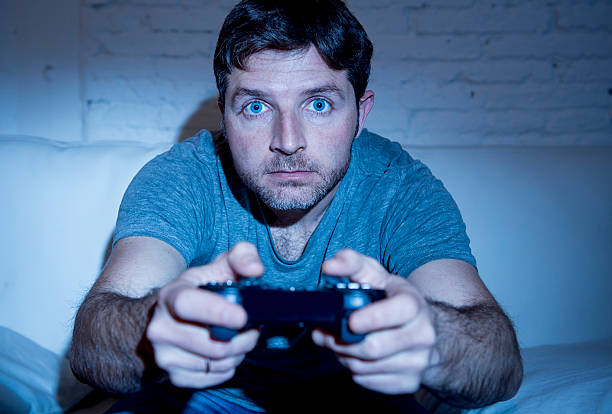 jeune heureux homme jouer à des jeux vidéo avec télécommande manette de jeu - video game joystick leisure games control photos et images de collection