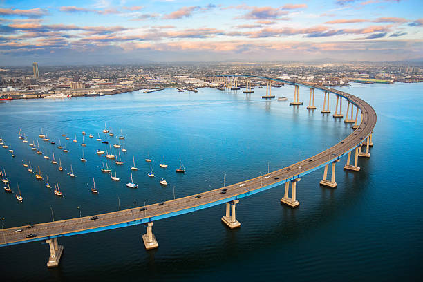 San Diego Coronado Bay Bridge From Above The unique curvature of the Coronado Bay Bridge spanning San Diego Harbor joining two cities; San Diego and Coronado.  I shot this image at dusk after a winter storm from a helicopter during a chartered photo flight at about 300 feet elevation. local landmark stock pictures, royalty-free photos & images