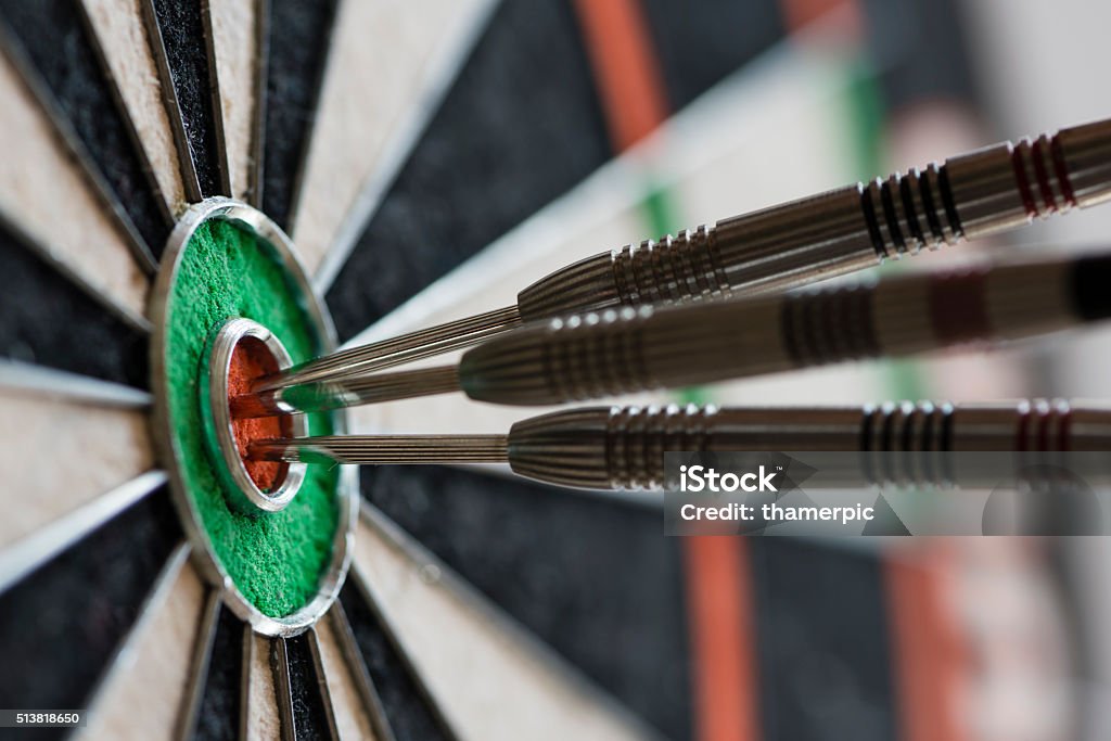 Darts hitting bull's eye on the dartboard Closeup view of silhouette of three darts sticking in a professional sisal dartboard. All three darts hit the inner bull / bull's eye / mark. Darts Stock Photo