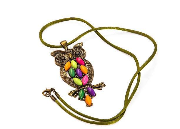 Owl necklace adorned with coloured stones on a silk cord isolated over white.Main colors: green, pink, violet, orange.