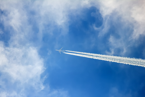 Silhouette of aircraft flying at high altitudes in the clouds and leaving contrail