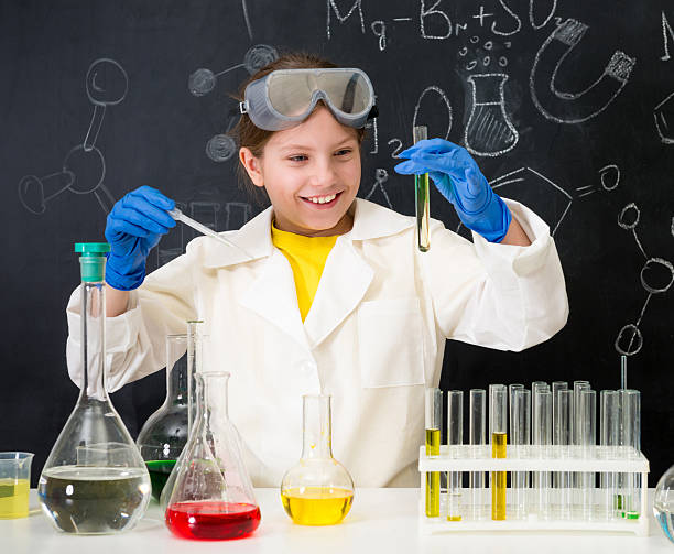 istock schoolgirl in white gown doing experiments with liquids 513821458