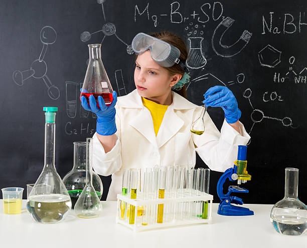 istock schoolgirl in white gown doing experiments with liquids 513821596