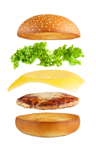 American food. Burger layers isolated. Separated burger layers isolated. Hamburger exposion. Cheeseburger flying fillings isolated at white background. Levitation of burger and cheese, meat, lettuce.