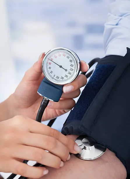 Cropped image of young female doctor checking blood pressure of businessman in clinic
