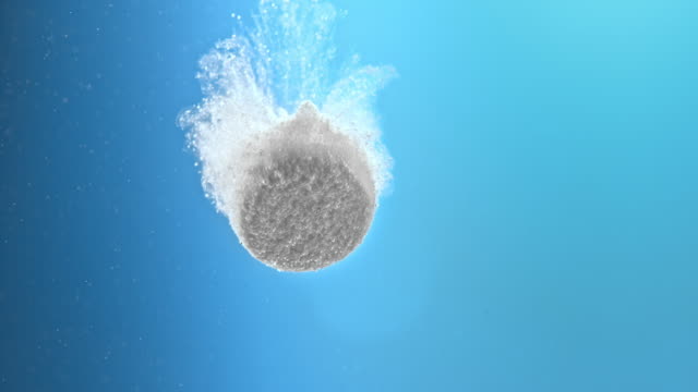 SLO MO Fizzing tablet dissolving on blue background