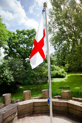 england flag on wooden fort flying against summer trees
