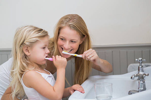 istock Happy mother and daughter brushing their teeth 513850483