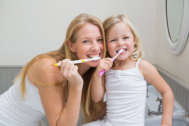 istock Happy mother and daughter brushing their teeth 513850489