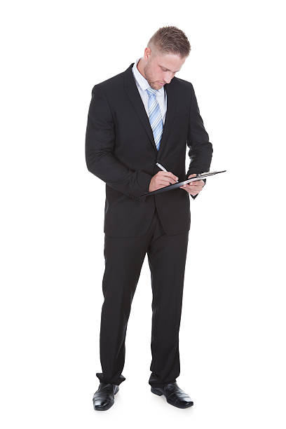 istock Businessman standing writing on a handheld clipboard 513853637