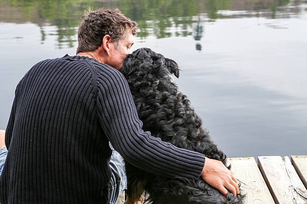 A man hugs his dog on the dock at the lake